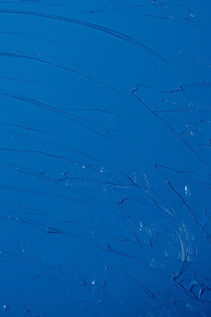 Close-up of a textured abstract painting with deep blue hues and dynamic brush strokes.